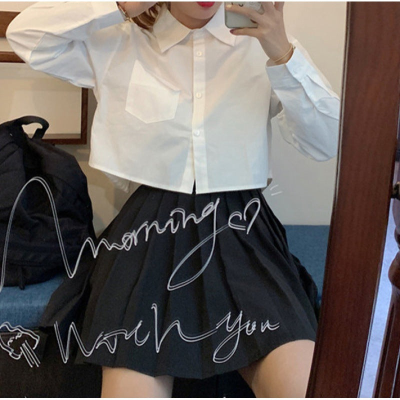 Shirt in White with Cropped Boxy Fit - white seated mirror view with black pleated skirt
