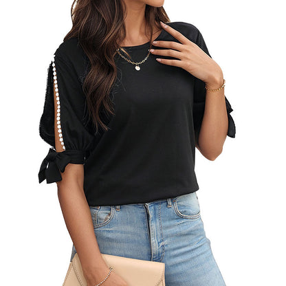 T-Shirt in Black with Pearl-Trim Cold-Shoulder Sleeves - black three-quarter front view with clutch